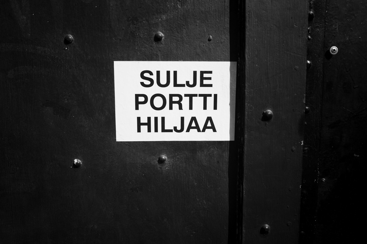 Close-up of a metal door with a sticker saying SULJE PORTTI HILJAA
