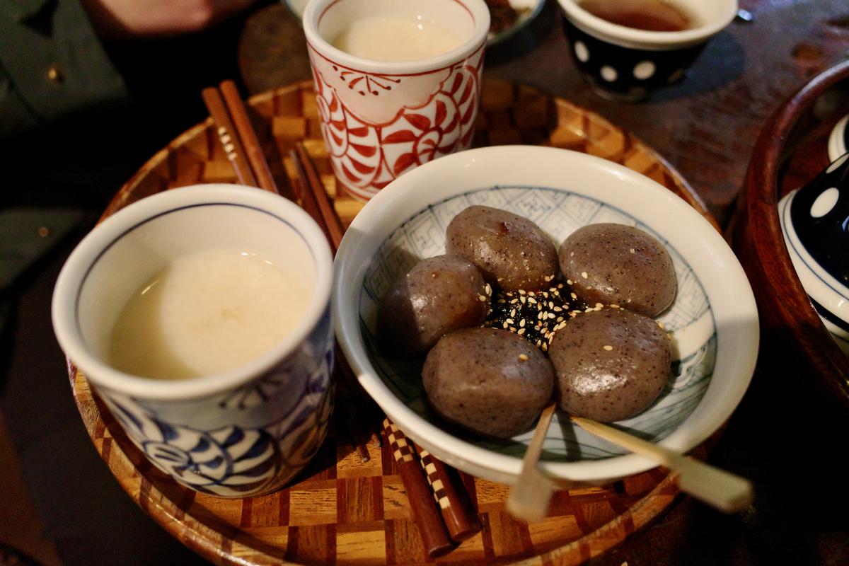 A tray with two cups of amazake and a plate of plum-sized konjac balls.